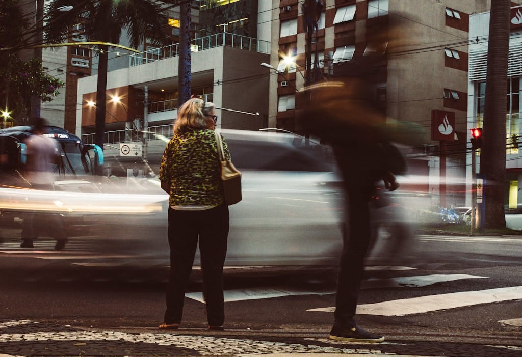 Blurred city street scene with pedestrians and vehicles in motion, showcasing urban hustle and bustle.