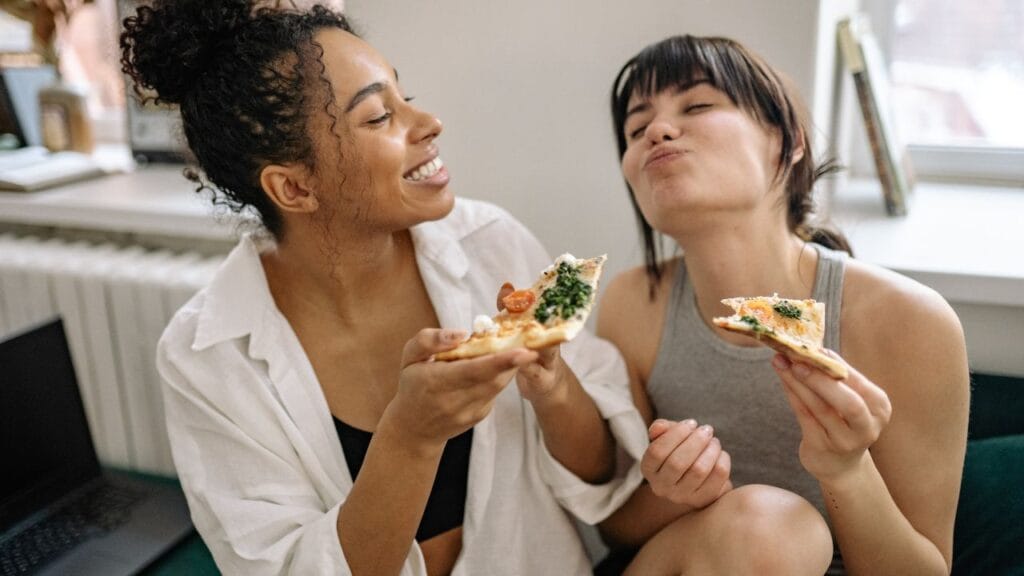 amigas sentadas feliz ao comer pizza